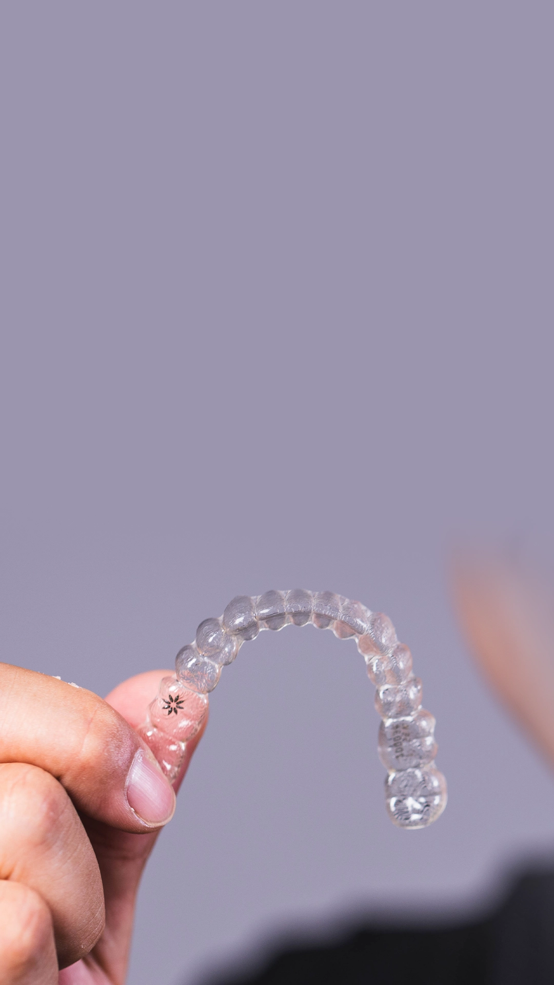 Mão segurando um alinhador invisível transparente