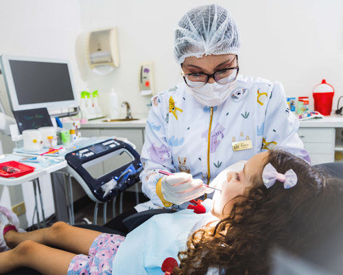 Atendimento de odontopediatria na Clínica IEM: profissional cuidando de uma criança na cadeira odontológica