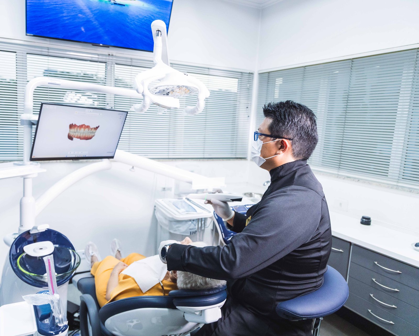Dr. Willian Saito operando scanner intraoral, com o escaneamento 3D exibido no monitor do consultório